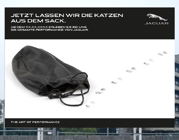 An image of a billboard outside of a construction site. 
                The billboard shows an empty black bag with paw prints leading out of it and the headline Jezt Lassen 
                Wir Die Katzen Aus Dem Sack.