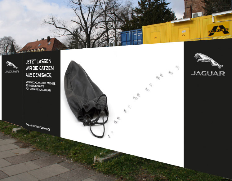 An image of a fence surrounding a construction site. 
                The fence is covered with a sign showing an empty black bag with paw prints leading out of it and the headline 
                Jezt Lassen Wir Die Katzen Aus Dem Sack.