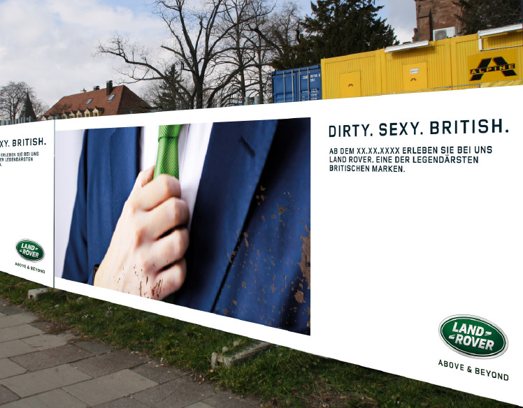 An image of a fence surrounding a construction site. 
                The fence is covered with a sign showing a close up of a person wearing a mud-splattered blue suit with a 
                green tie and the headline Dirty. Sexy. British.
