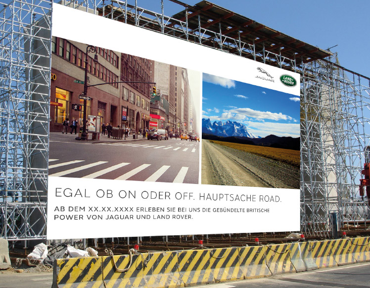 An image of scaffolding at a construction site. 
                The scaffolding is covered with a sign showing a split view of a city street and a dirt road with mountains in the background. 
                The headline reads Egal Ob On Oder Off. Hauptsache Road.
